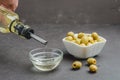 Olive oil pouring from bottle in bowl and fresh olives in ceramic plate and on dark stone table. Top view Royalty Free Stock Photo