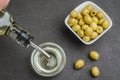 Olive oil pouring from bottle in bowl and fresh olives in ceramic plate and on dark stone table. Top view Royalty Free Stock Photo