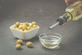 Olive oil pouring from bottle in bowl and fresh olives in ceramic plate and on dark stone table. Top view Royalty Free Stock Photo