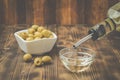 Olive oil pouring from bottle in bowl and fresh olives in ceramic plate and on wooden background Royalty Free Stock Photo