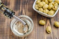 Olive oil pouring from bottle in bowl and fresh olives in ceramic plate and on wooden background. Top view Royalty Free Stock Photo