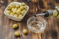 Olive oil pouring from bottle in bowl and fresh olives in ceramic plate and on wooden background. Top view Royalty Free Stock Photo