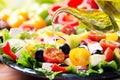Olive oil pouring into plate of greek salad Royalty Free Stock Photo