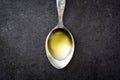 Olive oil on a spoon. Black slate background.
