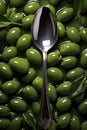 Olive oil in a spoon with green olive fruits, culinary background