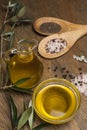 Olive oil, two spoon with salt and pepper on a wooden table