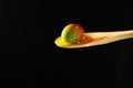 An olive in olive oil on a wood spoon in extra virgin olive oil on a black background