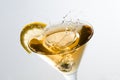 An olive splashing on a glass of martini with a slice of lemon