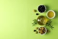 Olives, bottle and bowl with olive oil on green background Royalty Free Stock Photo