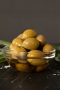Olives in an extra virgin olive oil placed in a glass bowl and green branches on a dark table with copy space, vertical shot Royalty Free Stock Photo