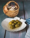 Olives in a flat sink and a wicker basket with sea shells, marine-themed paper napkins