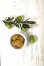 Olives in a porcelain bowl and young olive twig on wooden background