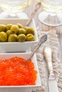 Olives and red caviar are in two white bowls