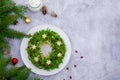 Olivier salad Christmas wreath with vegetables, meat, eggs and mayonnaise on a plate on a gray background.