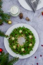 Olivier salad Christmas wreath with vegetables, meat, eggs and mayonnaise on a plate on a gray background.