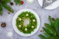 Olivier salad Christmas wreath with vegetables, meat sausage, eggs and mayonnaise on a plate on a gray background.