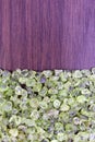 Olivine heap jewel on half brown varnished wood texture. Pile mineral pebbles background