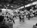 Blackwhite image - Multiple bouquets in white paper hanging from the ceiling in a hall of Flora Exposition with people around