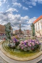 Olomouc, Czech Republic - 19 08 2021: Arion fountain with flowers against UNESCO monument The Holy Trinity Column.