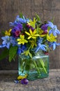 ÃÂ¡olorful spring flowers in a glass vase on old wooden background with space for text.