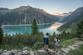 Olpererhutte, Austria - Aug 7, 2020: Two female trekkers take photo of glacier reservoir at sunset hour