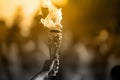 Olympic torch. A hand holds the cup with an torch against a blurred gold background Royalty Free Stock Photo
