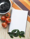 Kitchen note book on a tablecloth with tomatoes a bowl Royalty Free Stock Photo