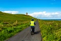 Woman cycling among the Irish countryside with the Doonagore Castle tower and the sea in the background Royalty Free Stock Photo