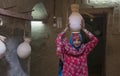 Omani lady in iraditional outfit putting a water jar on her head