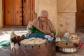 Omani woman in traditional dress preparing a crispy crepe in Nizwa fort