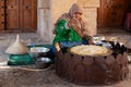 Omani woman in traditional dress preparing a crispy crepe in Nizwa fort