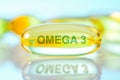 Omega 3 capsule on the gloss light blue surface with reflections and title Omega. Four fish oil capsules, close-up macro high