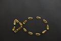 Omega 3 capsules in fish shape on black dark background. Fish oil pills. Top view. Dietary supplements. Health support and