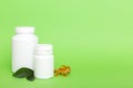 Omega-3 capsules lie in white bottle on a table with green leaves background. Fish oil tablets. Biologically active Royalty Free Stock Photo