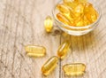 Omega 3 fish liver oil capsules in small glass bowl. Close up of golden translucent pills. Healthy fatty acids nutritional