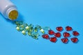 Omega 3 polyunsaturated fatty acids and red hearts pour out from a white plastic jar on a blue background. Prevention