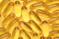 Omega 3 softgels or Fish oil capsules, yellow pills background.