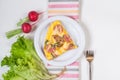 Omelet with croutons, sausages, cheese and dill in a white plate and vegetables Royalty Free Stock Photo