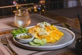 Omelet, fried beaten eggs on a white plate. Placed on a wooden table ready to eat.