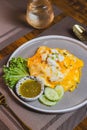 Omelet, fried beaten eggs on a white plate. Placed on a wooden table ready to eat.