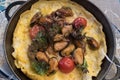 Omelet with mussels, cherry tomatoes and green onions on a ceramic plat