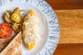 Omelet with potato, tomatoes parsley and feta cheese and bread in white plate on wooden table Royalty Free Stock Photo