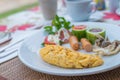 Omelet with vegetable salad and hot dogs on white plate.