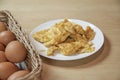 Omelets in white plate, basket of eggs on table in home kitchen Royalty Free Stock Photo