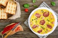 Omelette with ham, salami, cheese and greens on a plate on a wooden background.