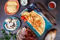 Omelette with prosciutto, slices ham, mushrooms, greens, cheese and tomato sauce on dark wooden background. Royalty Free Stock Photo