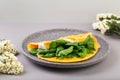 Omelette stuffed with spinach and cheese for a breakfast, with flowers on table Royalty Free Stock Photo
