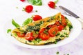 Omelette with tomatoes, spinach and green onion on white plate.