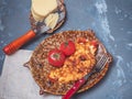 Omelette with vegetables and cheese on a decorative plate and two whole red tomatoes with leaves