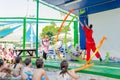 Omer, ISRAEL -Girl gymnast in red kimono jumping with colored ribbons on the open stage in front of children, July 25, 2015